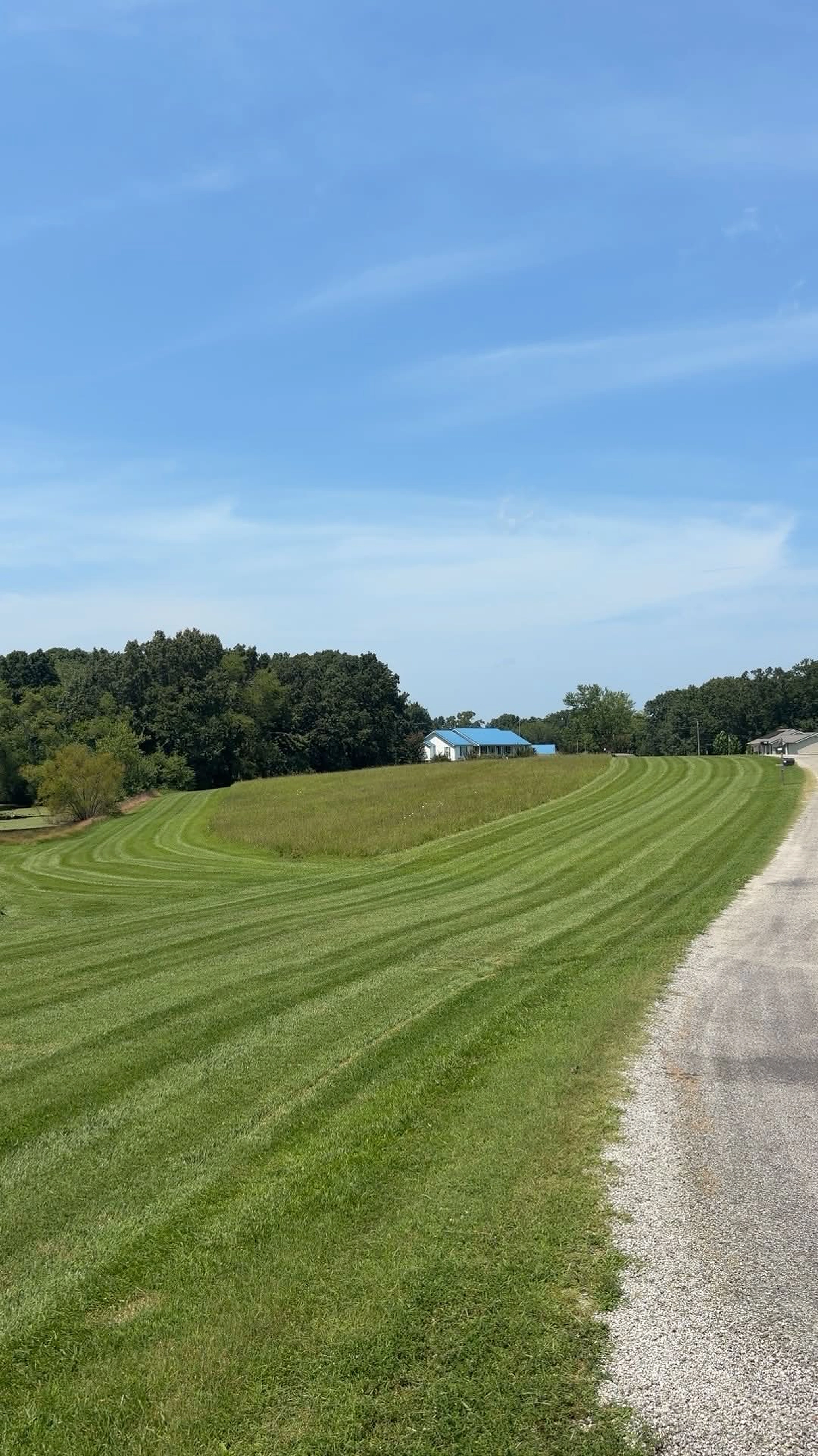 Freshly striped lawn beside a country road maintained by JL Lawn Services